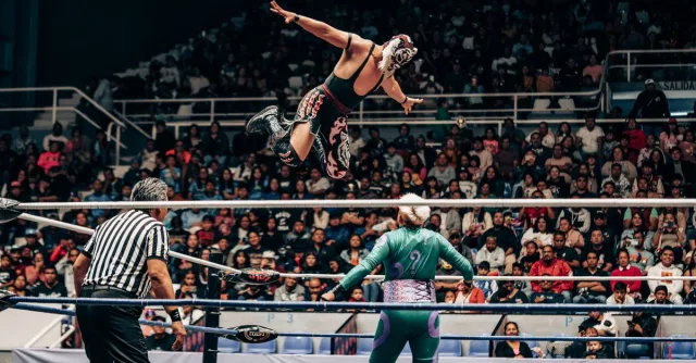 Action-packed shot of a Lucha Libre match in a crowded arena.