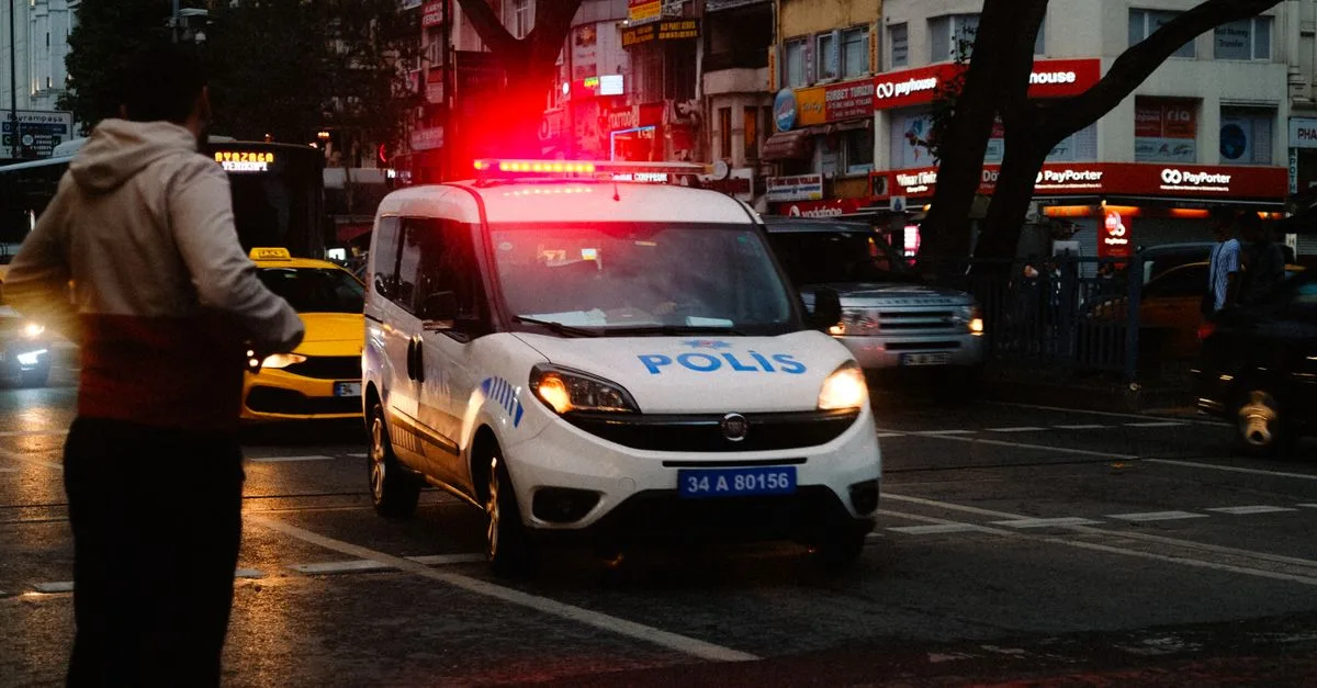 A police car with lights flashing in an urban setting at night, capturing the essence of city life.