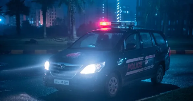 A Toyota police car patrols under city lights at night in Uttar Pradesh, India.