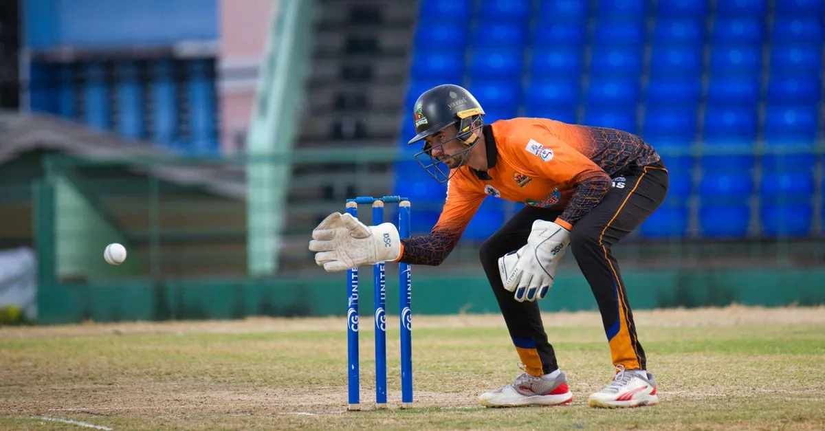 Focused wicketkeeper on cricket field in Basseterre, Saint Kitts and Nevis, during a daytime match.