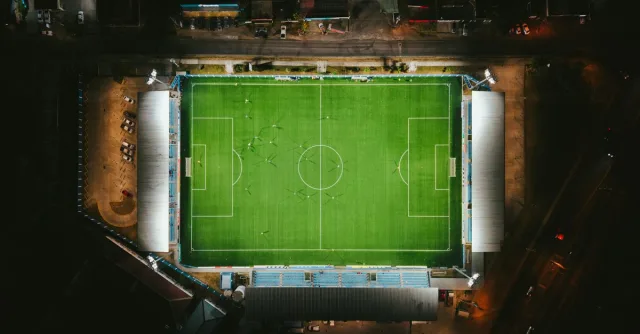 Aerial shot of a brightly lit soccer stadium at night with players on the field.