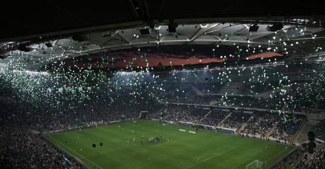 A crowded stadium at twilight with balloons filling the sky, creating a festive atmosphere.