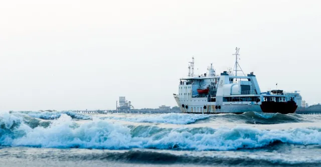 A large ship sails through the waves at Kochi Harbour, Kerala, India.