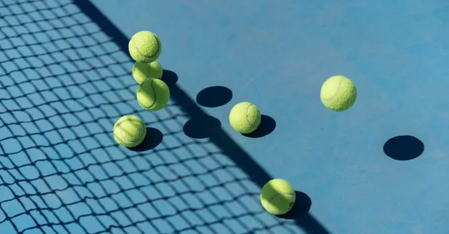 Tennis balls scattered on a blue court casting shadows, captured from above for a high-energy sports vibe.