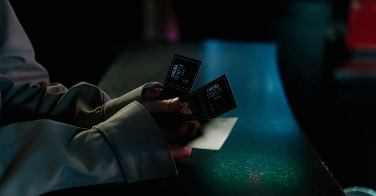 Moody image of a person holding cinema tickets at night, highlighting anticipation of a movie night.