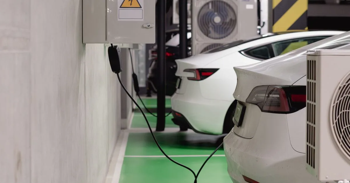Electric vehicles charging at an indoor station in a modern underground garage.