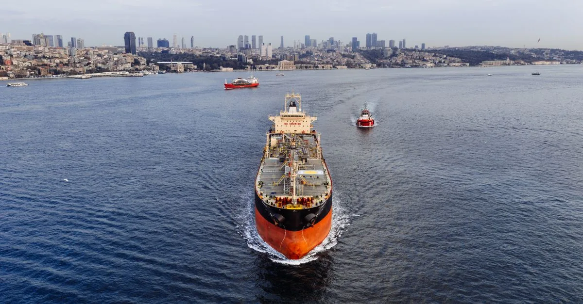 A stunning aerial shot of a cargo ship navigating the Bosphorus Strait in Istanbul, Turkey, with a city skyline.