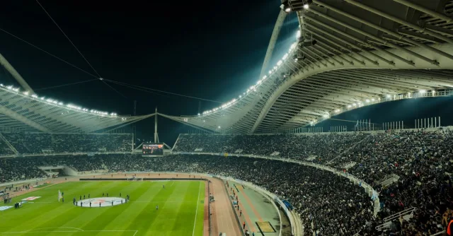 A crowded soccer stadium under bright lights at night, capturing the excitement of a live sports event.