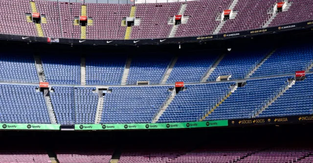 Wide-angle view of the empty stands at Camp Nou Stadium in Barcelona displaying vibrant seat colors.