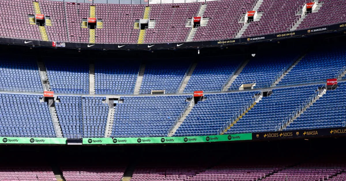 Wide-angle view of the empty stands at Camp Nou Stadium in Barcelona displaying vibrant seat colors.