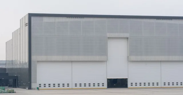 Front view of a large modern warehouse with closed doors, showcasing industrial architecture