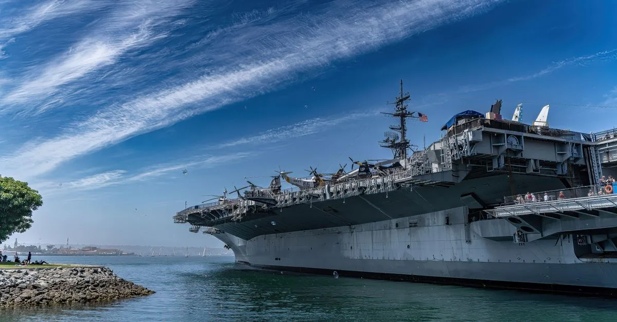 USS Midway Museum ship docked in San Diego harbor on a clear day, showcasing naval history.