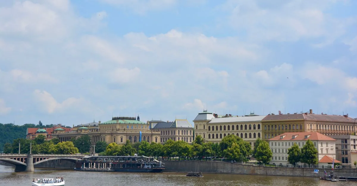 A picturesque view of Prague with the Vltava River, historical buildings, and a bridge.