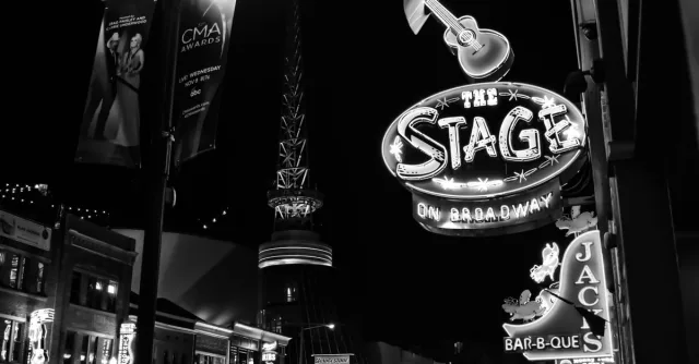 Black and white photo capturing the lively neon-lit signs of Broadway Street, Nashville at night.