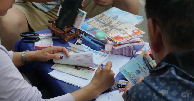 Casual gathering playing lottery outdoors in Ha Giang, Vietnam, capturing cultural street life.
