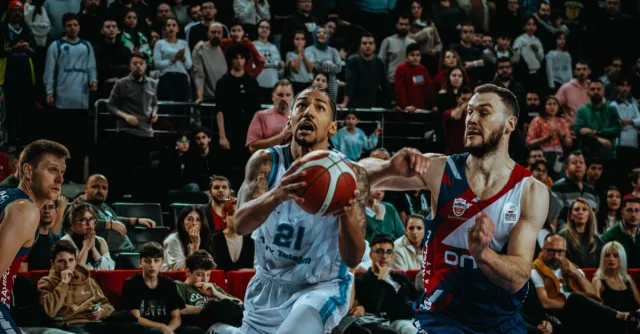 Dynamic action shot from a live basketball game capturing the competition and audience involvement.