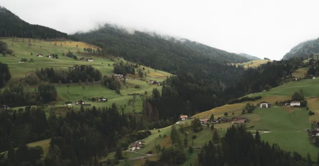 Explore a serene alpine landscape in Austria featuring rolling hills and traditional houses.