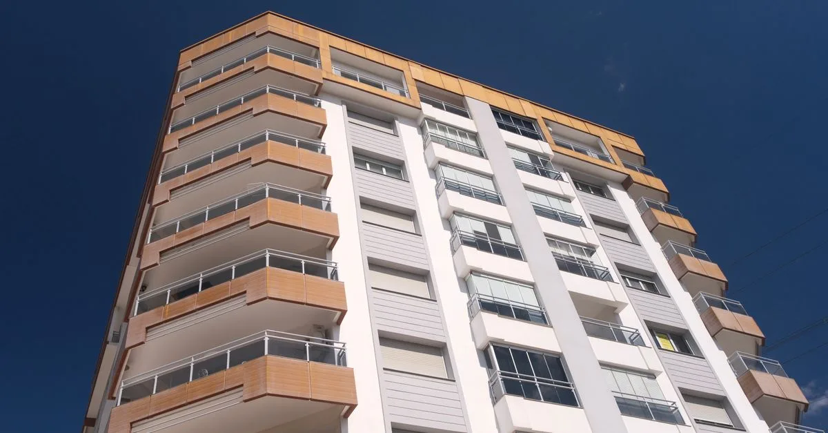 A modern residential building with balconies in İzmir, Türkiye under a clear blue sky.