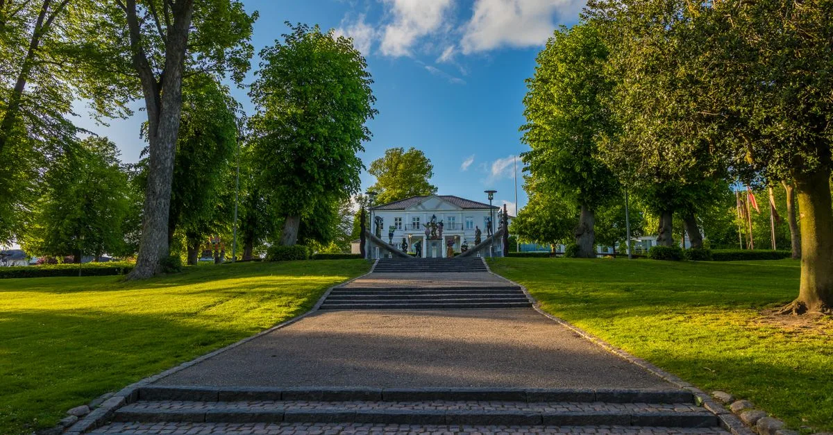 Lush green park in Horsens, Denmark with a scenic pathway leading to a historic building.