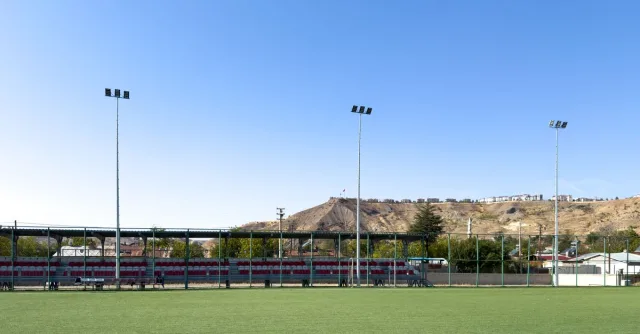 A wide-angle shot of a sports field in Palu, Elazığ, Türkiye with clear blue sky.