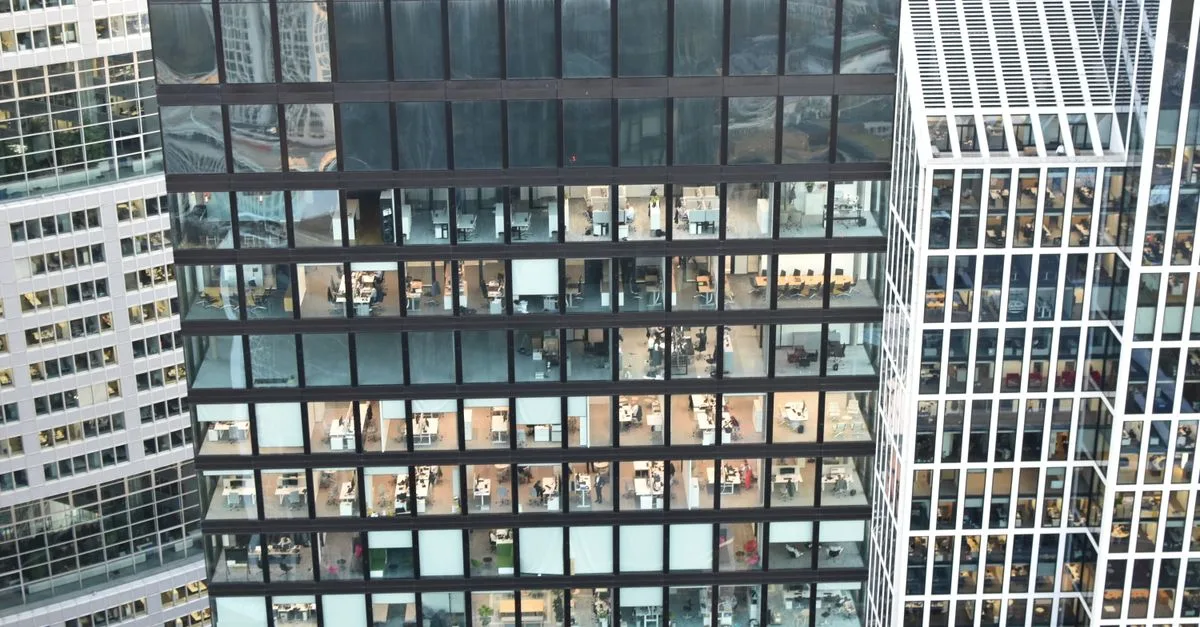 High-rise building facade with visible office interiors, showcasing urban architecture.