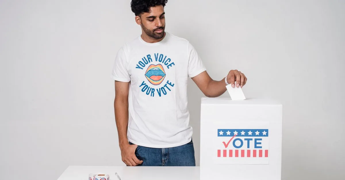 Young man casting a vote into a ballot box on a white background promoting democracy.
