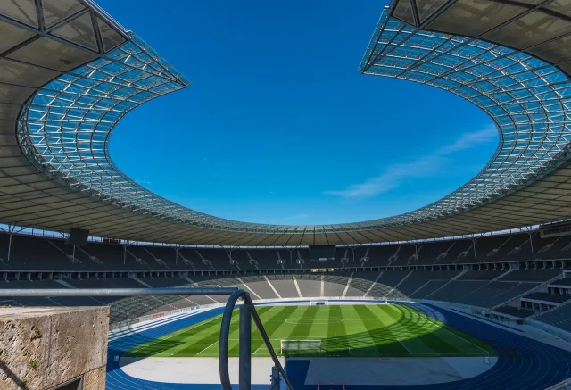 An empty football stadium pitch under daylight.