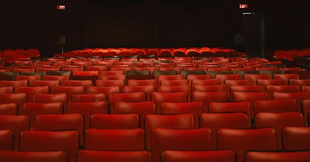 Rows of empty red seats inside a classic movie theater with a vintage ambiance.