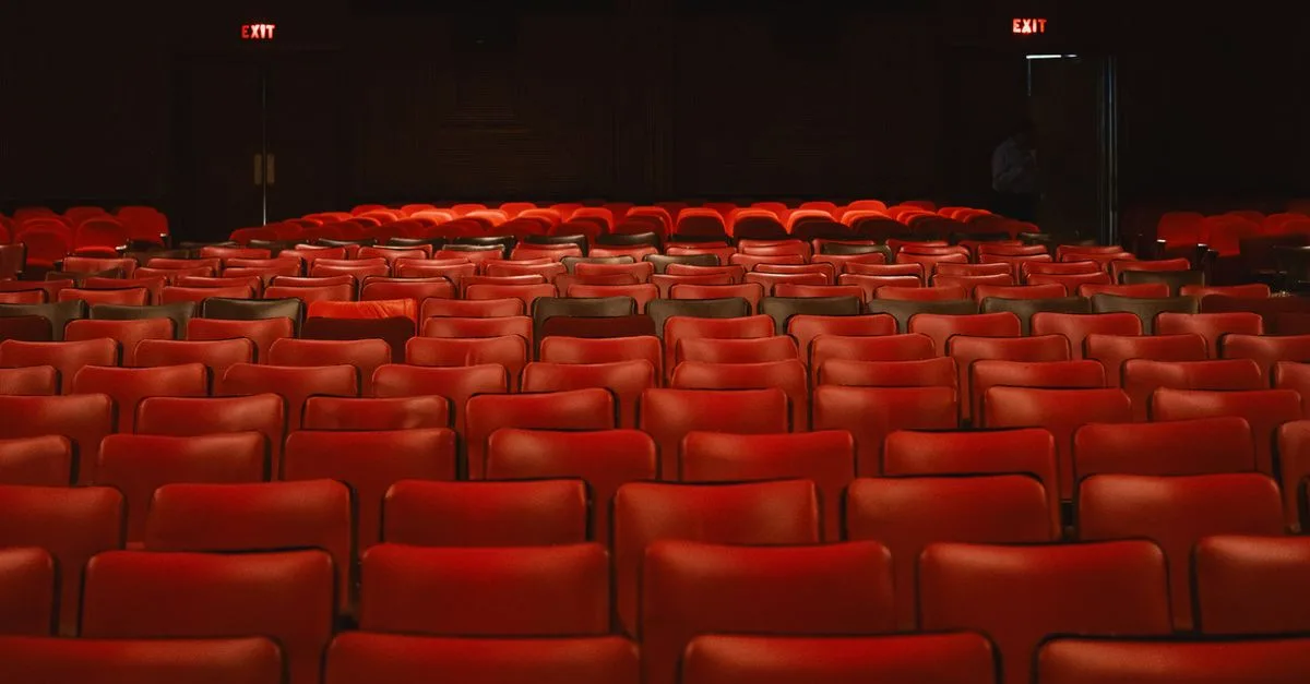 Rows of empty red seats inside a classic movie theater with a vintage ambiance.