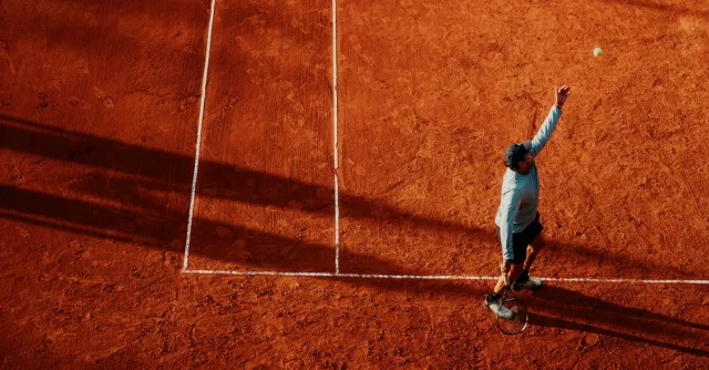 Aerial view of a tennis player serving on a clay court in Buenos Aires, Argentina.