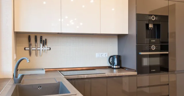 Interior of kitchen with minimalist glossy furniture and modern appliances in light contemporary apartment