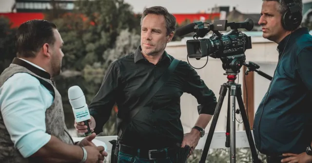 Outdoor interview with a professional news crew capturing footage using high-tech equipment.