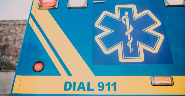 Close-up of an ambulance with star of life symbol and 'Dial 911' text.