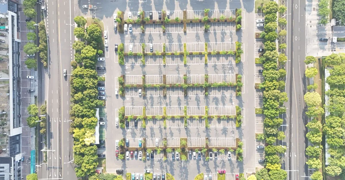 Aerial view showcasing an organized city parking lot lined with trees and parked cars.
