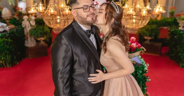A couple dressed elegantly enjoys a luxurious indoor celebration, surrounded by ornate decor and vibrant lighting.