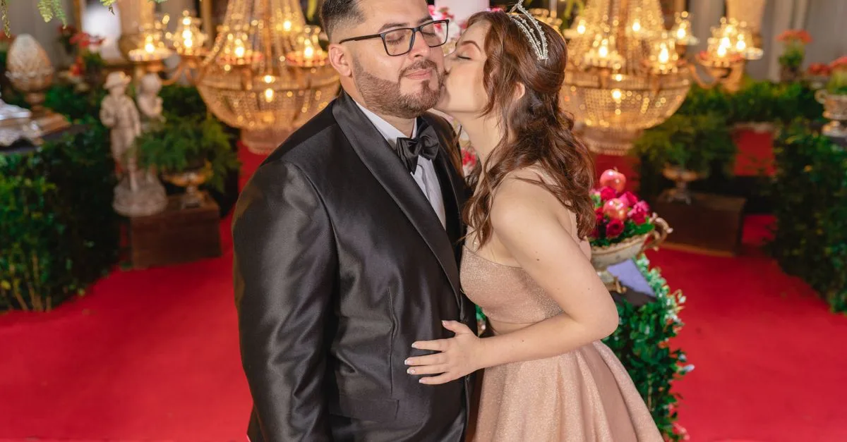 A couple dressed elegantly enjoys a luxurious indoor celebration, surrounded by ornate decor and vibrant lighting.
