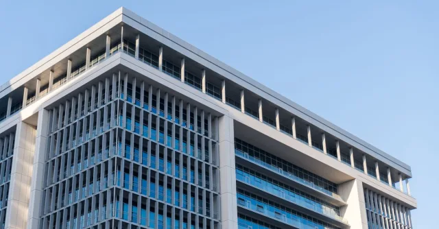 Contemporary highrise building with glass facade under a clear blue sky.
