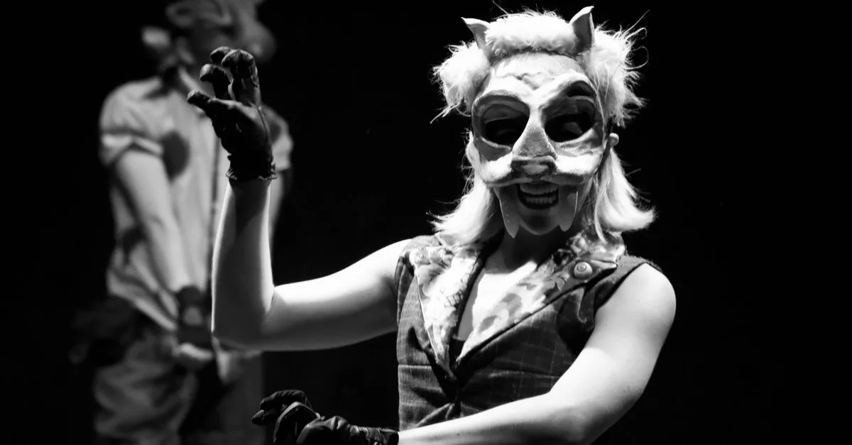A captivating black and white image of actors in animal masks performing on stage, creating an eerie atmosphere.
