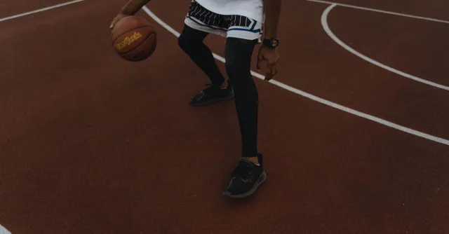 Dynamic shot of a basketball player dribbling on an outdoor court, showcasing athleticism.