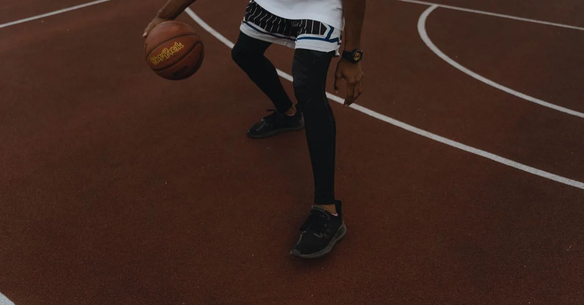 Dynamic shot of a basketball player dribbling on an outdoor court, showcasing athleticism.