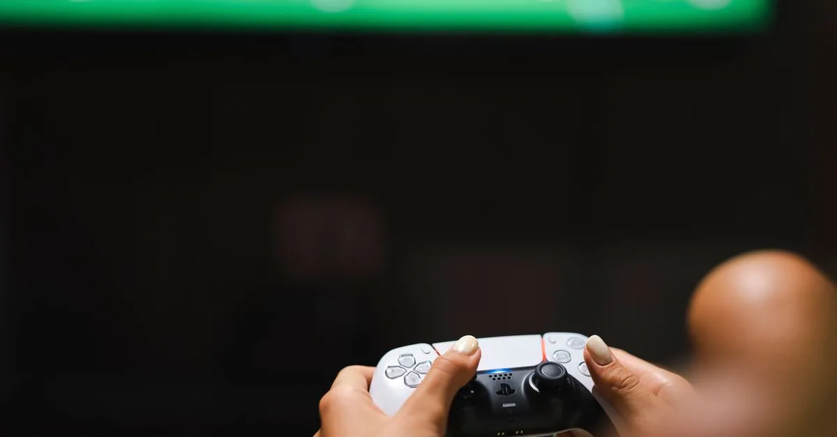 Close-up of hands holding a modern video game controller while gaming.