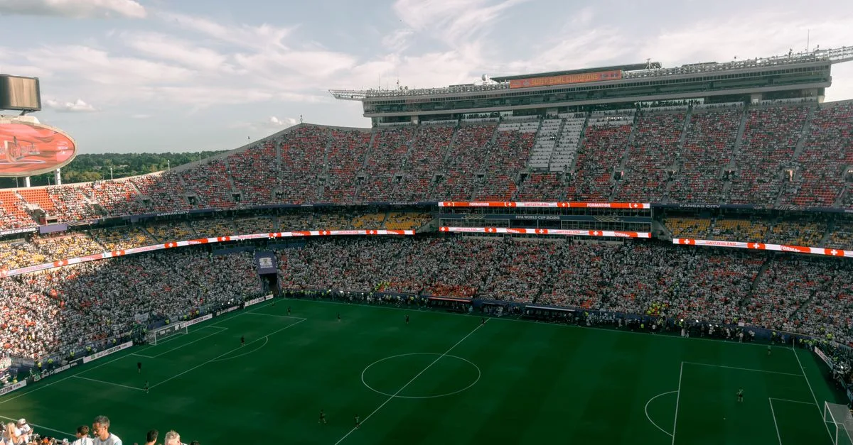 Aerial view of a lively soccer match in a bustling outdoor stadium filled with enthusiastic fans.