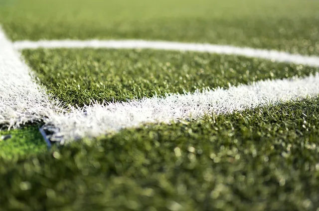 A wide view of a professional football stadium pitch during the day.