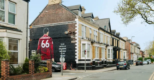 Urban street scene in Liverpool featuring a prominent mural of Trent Alexander-Arnold.