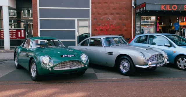 Two vintage Aston Martin cars parked on a street in Amsterdam.