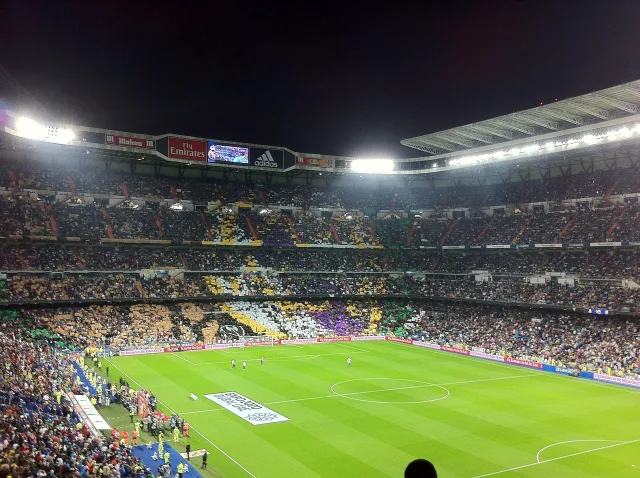A professional football stadium illuminated by bright floodlights at night.