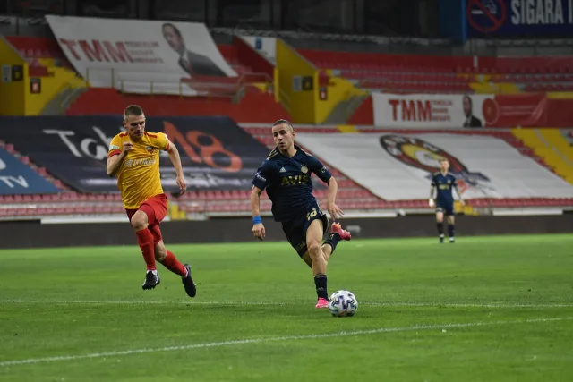 A wide shot of a professional football stadium pitch during the day.