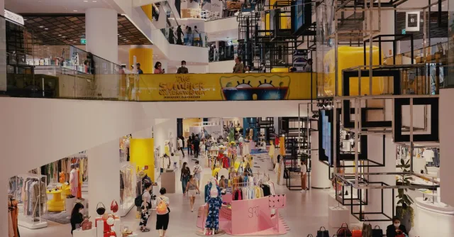 Vibrant mall filled with shoppers, contemporary decor, and stylish fashion outlets.
