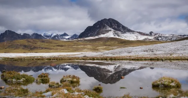 Breathtaking view of Andes mountains reflecting in a serene lake in Cusco, Peru.