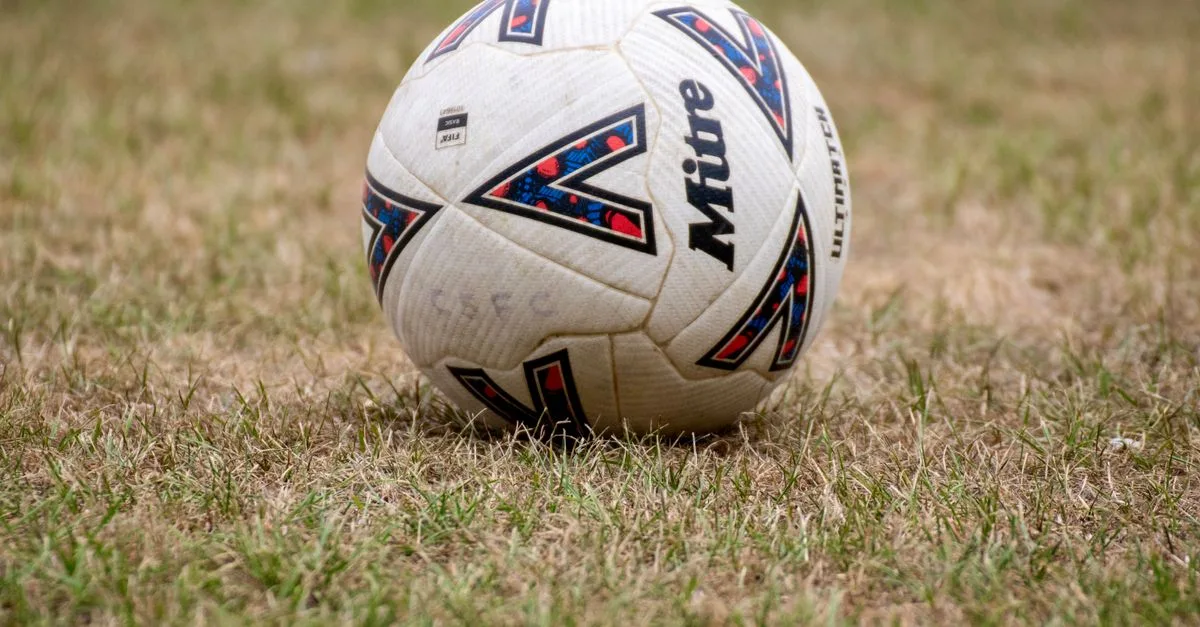 Close-up of a soccer ball on dry grass in Tipton, England. Perfect for sports and recreation themes.